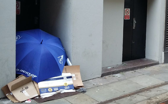 Umberella and cardboards stack against a wall.