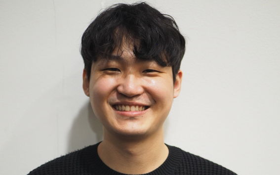 Jinsu Son happily mailing reward the camera in a black knitted sweater.