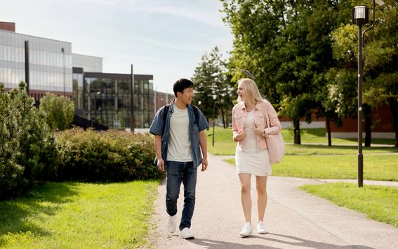 Two students walking on campus, chattering and laughing together.