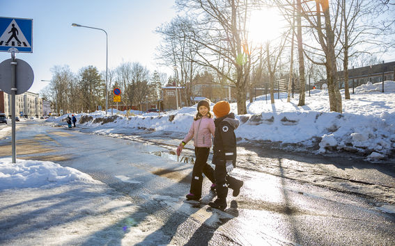A photo of two young children crossing the street together.