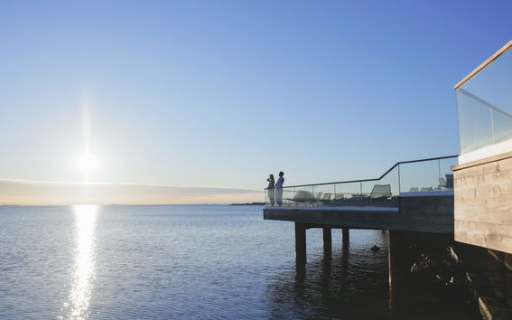 Two people standing on the terrace of Löyly after a sauna bath, looking out to the sea.