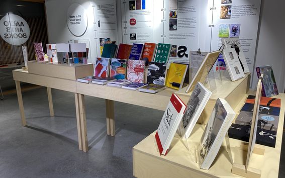 Seinäplansseja ja kirjapöytiä näyttelytilasta.