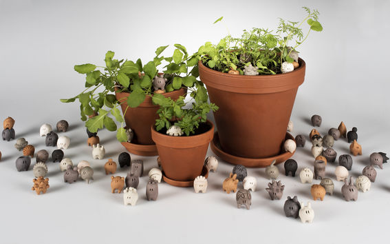 three plants in pots and heaps of little ceramic creatures around them