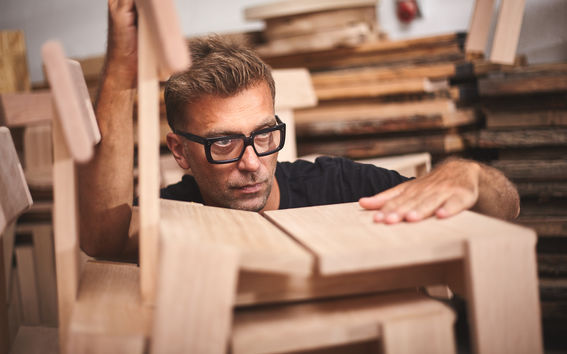 Man looking at a wooden chair, holding it  