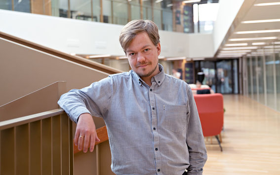The picture shows Tilman Bauer near the stairs in the School of Business building.