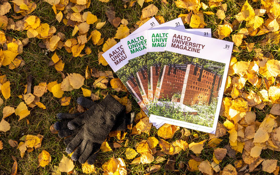 Neljä Aalto University Magazinea syksyisellä nurmikolla keltaisten lehtien päällä. Julkaisujen vieressä on mustat neulehansikkaat.