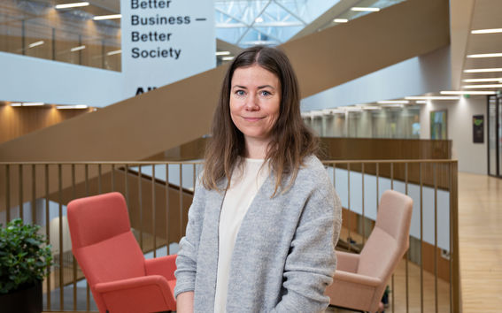 Kuvassa saara Hietanen seisoo Kauppakorkeakoulun aulassa portaiden edessä. 