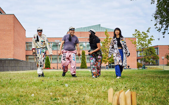 Neljä Aallon opiskelijaa pelaamassa mölkkyä yllään opiskelijahaalarit ja -takit. 