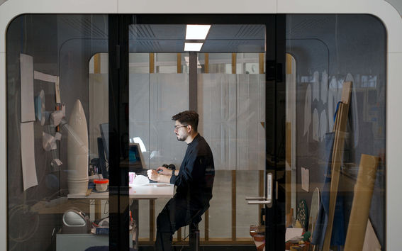Person sitting in office with glass walls working on their laptop