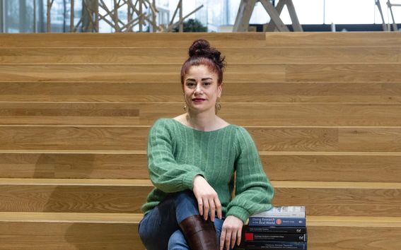 Nainen istuu portailla kameraan katsoen.