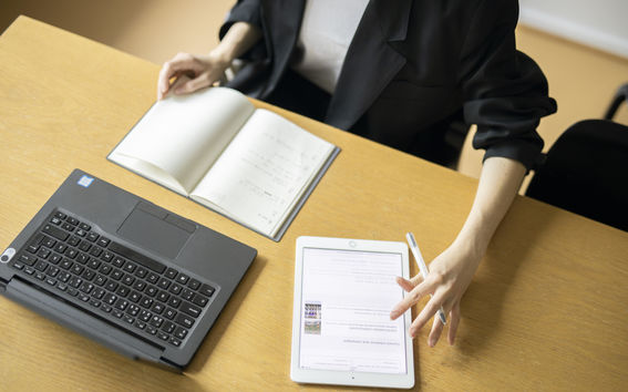 Henkilö työskentelee sekä kannettavalla tietokoneella että iPadillä.