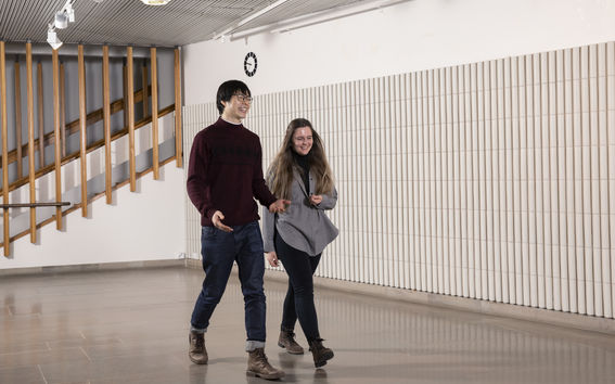 Kaksi ihmistä kävelee käytävällä ja puhuu keskenään.
