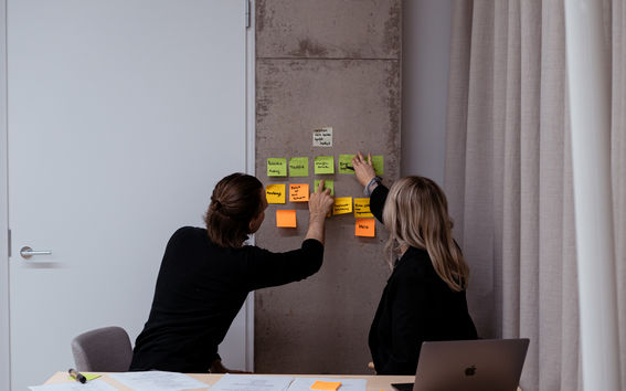 Två elever sorterar post-it-lapparna på väggen.