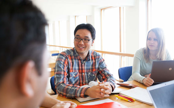 Students chatting with each other, with computers and books on the table