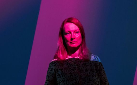 Sini-punasävyisessä henkilökuvassa on dramaattinen tunnelma ja vahvat varjot. Alma Muukka-Marjovuon ilme on vakava. Kuva: Aleksi Poutanen.