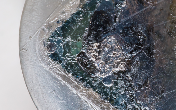 A close-up photo of an epoxy sample with different shades of blue, and some green and gray colouring as well