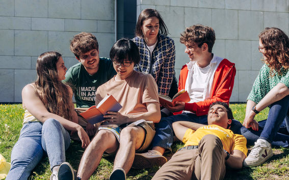 Aalto University students sitting outside campus in the summer sun.