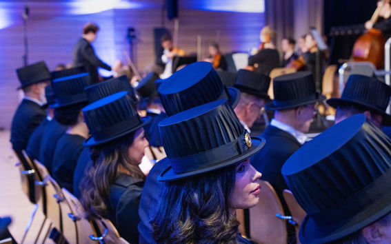 Rows of doctors sitting with their doctoral hats on, photographed from behind