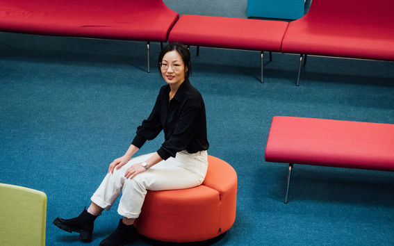 Student Qimeng Wang is sitting in the library lobby area.