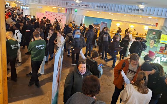 A crowd of people in a lobby where there are roll-ups and branded pop up walls