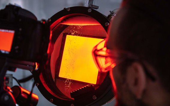 Tutkija katsoo keltaisen ja punaisen sävyistä materiaalinäytettä 