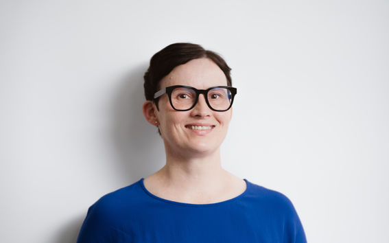 Sinipaitainen nainen, jolla on lyhyet tummat hiukset ja tummasankaiset silmälasit 