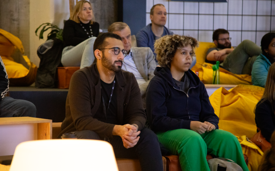 Audience members sitting on bright yellow beanbag chairs.