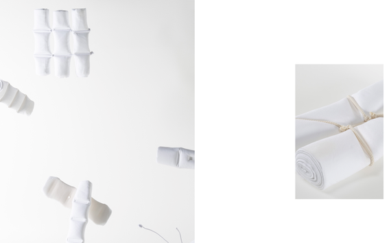 A collection of white rolled up textiles, some tied together, others pressed