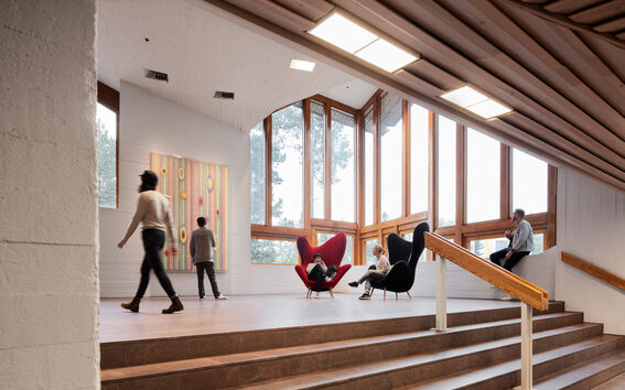 People in a modern staircase with large windows, colourful wall art, and stylish chairs.