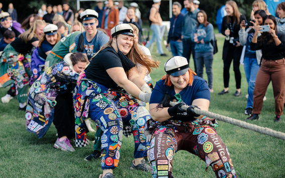 People in student overalls and white student caps in the rope pulling competition