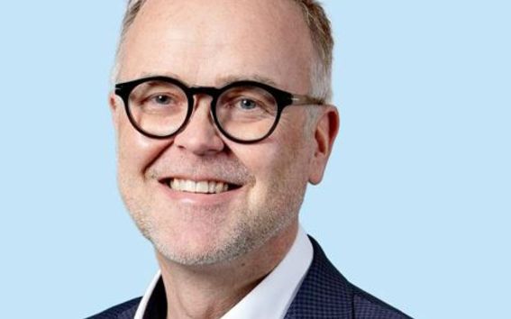 Ihminen katsoo lähikuvassa kameraan hymyillen.