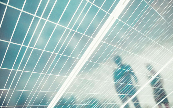 Aurinkopaneeli, jossa kahden ihmisen heijastus kuvattuna. 