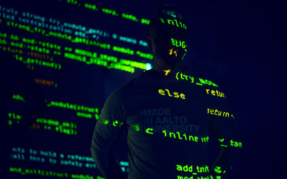 Kuvituskuva, jossa tummaa taustaa vasten koodia ja ihminen.