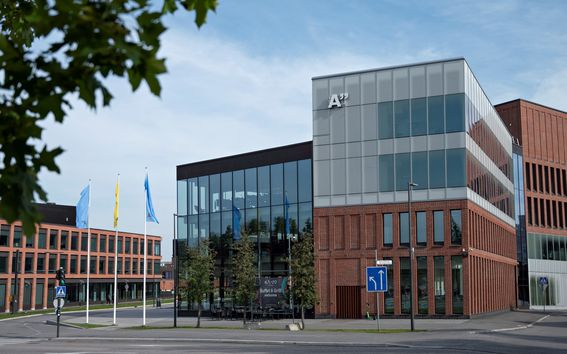 Kuvassa näkyy Kauppakorkeakoulun rakennus, sen vieressä oleva Kide-rakennus, sekä lipputangot ja puun oksa syksyisenä selkeänä päivänä. 