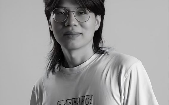 A black and white photo of Kun wearing glasses and a T-shirt.