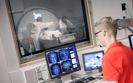 Man looking at a computer monitor with brain data in an MRI lab.