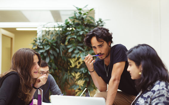 Joukko opiskelijoita pöydän ääressä.