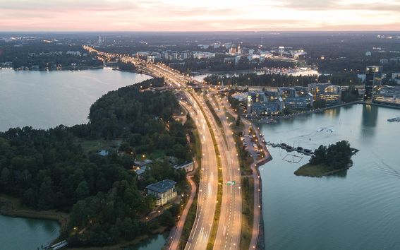A lit motorway crossing the sea, with buildings and sky visible