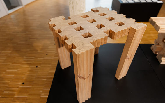 Puinen pöytä, jolla on ainutlaatuinen kuvio päällä ja tukevat jalat, sijoitettu puiselle lattialle sisätiloissa.