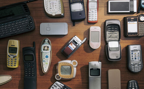 Kokoelma erilaisia vanhoja matkapuhelimia puisella pinnalla.