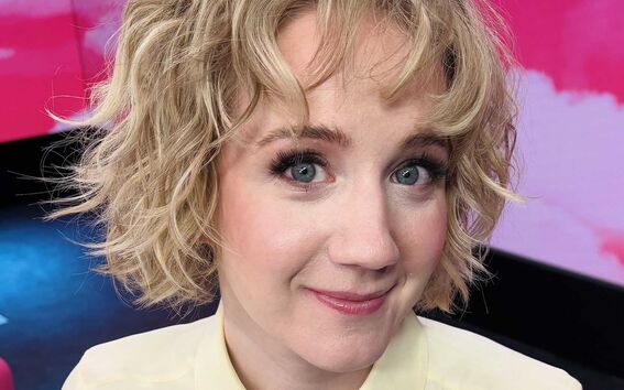 Kuvassa Anniina Valtonen, jolla on laineikkaat vaaleat hiukset ja vaalea paita.