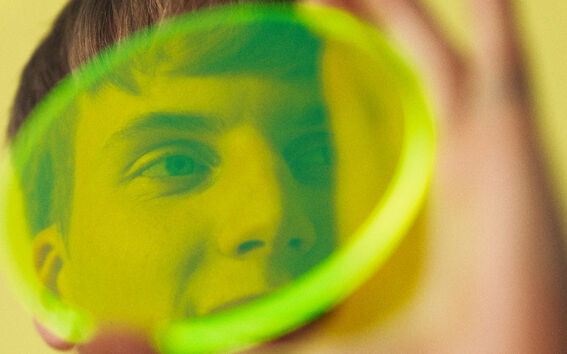 Person med grön skjorta och svart undertröja som håller ett limegrönt genomskinligt föremål