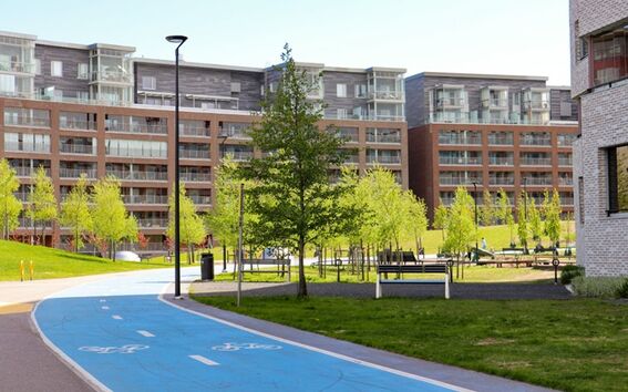 Modernit kerrostalot parvekkeineen, puita ja pyörätie etualalla.