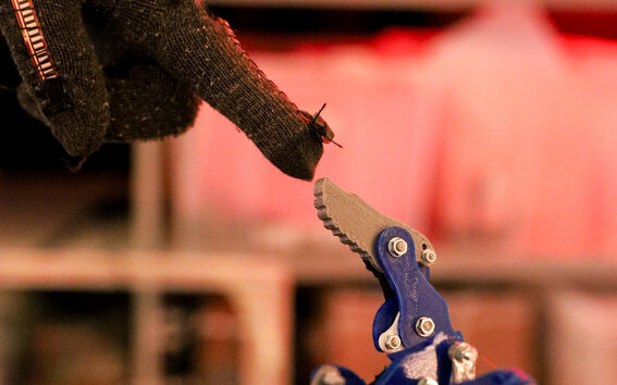 A gloved hand touches the finger of its robotic counterpart.