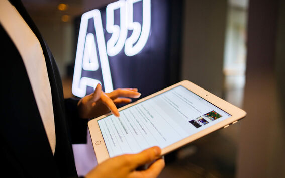 Person som använder en surfplatta bredvid en neonskylt med citattecken.