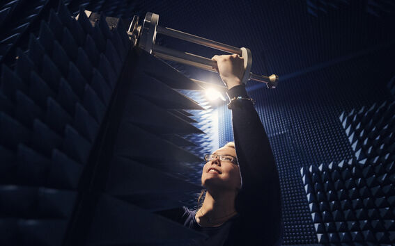 Henkilö säätämässä laitteita kaikumattomassa huoneessa, jossa on äänieristekiilat seinillä.