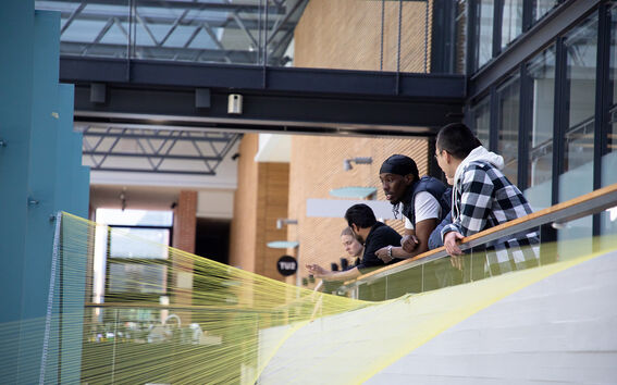 Opiskelijoita nojaamassa parven kaiteeseen.