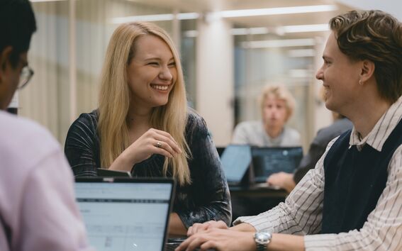 People working on laptops in a modern office space with glass walls.