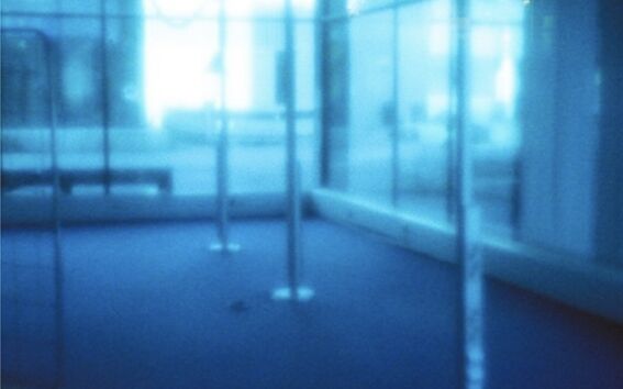 Blurry image of an empty room with large windows and metal poles. It's difficult to discern specific details.