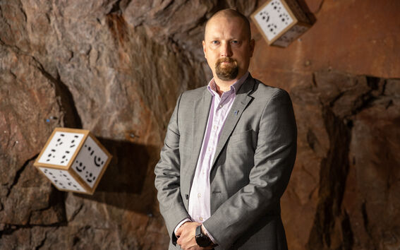 Apulaisprofessori Lauri Uotinen maanalaisten tutkimusten laboratoriossa. Kallioseinässä kaksi fotogrammetriassa käytettäviä automaattitunnistettavia merkkejä.